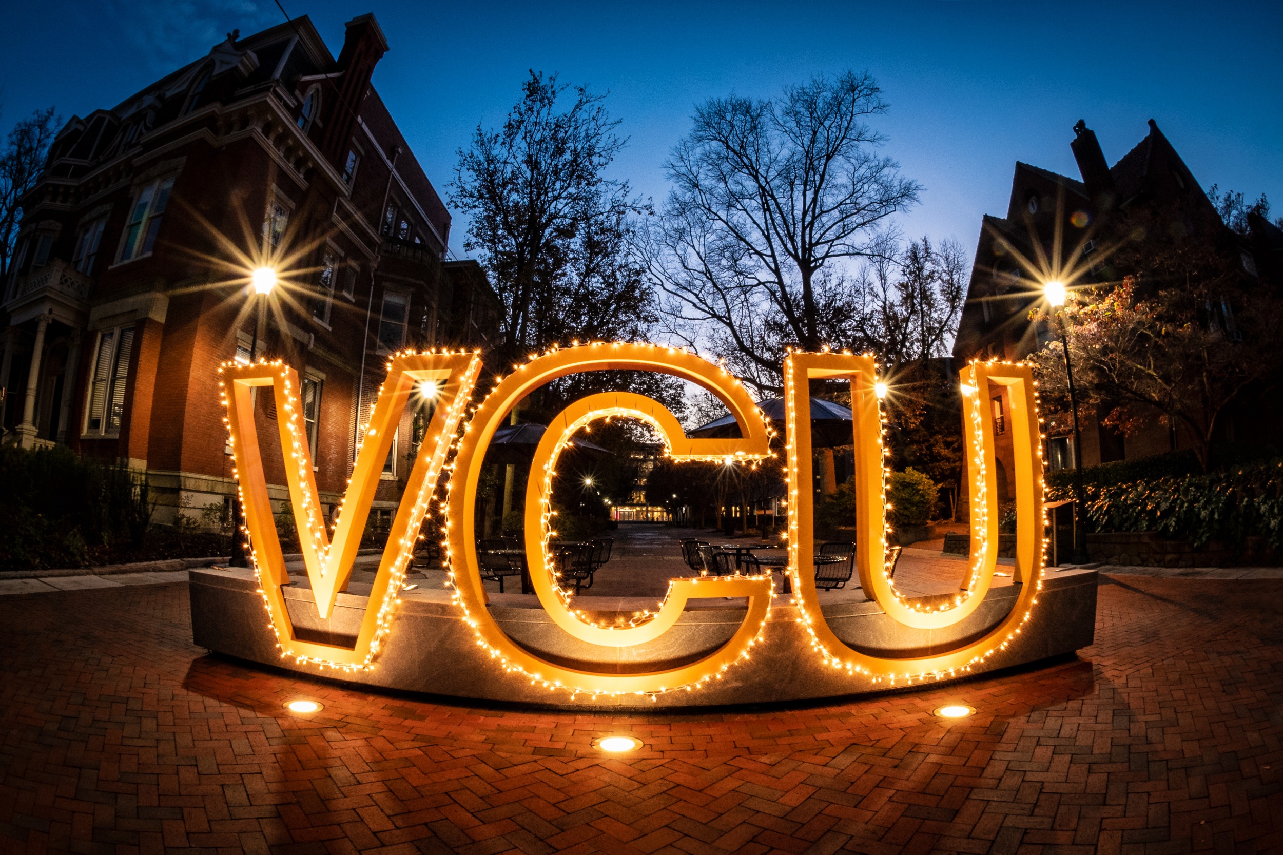 The letters VCU outlined with lights, lit up at night