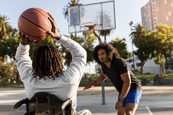 Two people playing basketball. One is in a wheelchair holding the ball